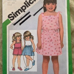 Può includere: Modello di cucito Simplicity numero 5121 per un abito da bambina. Il modello comprende due taglie, 5 e 6. Il modello mostra un abito rosa con stampa floreale bianca e un abito bianco con strisce blu. Il modello include anche istruzioni per la realizzazione dell'abito.