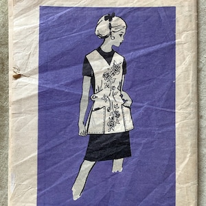 May include: A vintage sewing pattern for a dress with a floral print. The pattern is for size medium and is printed on a white background with a purple border. The pattern number is 4655.