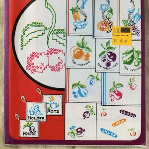 May include: A vintage embroidery pattern sheet with the title "Garden Fruits and Vegetables to Brighten Your Kitchen". The sheet features a variety of colorful embroidery designs, including cherries, grapes, and a teapot. The sheet is labeled "Vogart 211" and is a repeat transfer pattern.