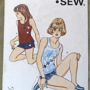 Puede incluir: Un patrón de costura vintage para un conjunto de camiseta sin mangas y pantalones cortos para niñas. El patrón es para las tallas 8-10-12-14. El patrón se llama "KWIK-SEW" y el número de patrón es 1077.