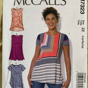 May include: Sewing pattern McCall's M7323 size ZZ (Lrg-Xlg-Xxl) for a women's top with four different styles. The pattern includes a sleeveless top with a diagonal stripe pattern, a short-sleeved top with a solid colour, a short-sleeved top with a striped pattern, and a short-sleeved top with a diagonal stripe pattern.