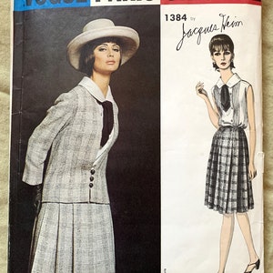 May include: Vogue Paris Original sewing pattern number 1384 by Jacques Heim. The pattern features two models wearing plaid dresses. One model is wearing a hat and a jacket. The other model is wearing a sleeveless dress.
