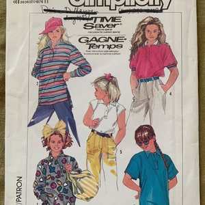 Puede incluir: Patrón de costura Simplicity número 1779 para blusas y pantalones de niña. El patrón incluye cuatro estilos diferentes: una blusa de manga larga a rayas, una blusa de manga corta blanca, un pantalón amarillo, una blusa de manga corta azul y una blusa de manga larga estampada con una bolsa de mano.