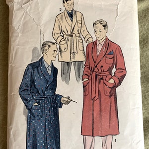 May include: Vintage sewing pattern for a men's robe. The pattern shows three different styles of robes, one with a polka dot pattern, one with a solid red color, and one with a solid beige color. The pattern is labeled "Advance, The Easy Printed Pattern!" and "Medium".
