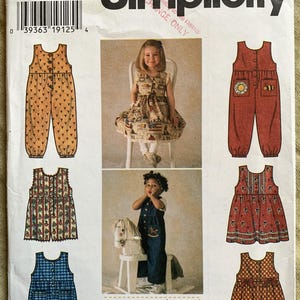 Op de afbeelding: Een naaipatroon voor kinderkleding, Simplicity patroon nummer 7213, maat BB 2, 3, 4. Het patroon bevat vijf verschillende stijlen: een gele jumpsuit met knoopsluiting, een rode jumpsuit met knoopsluiting en bijen- en bloemenborduurwerk, een rood-wit gestreepte jurk, een blauw-wit geruite jurk en een blauwe denim jumpsuit met knoopsluiting en een paardenprint.