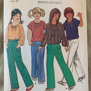 May include: A vintage sewing pattern for girls' clothing, featuring four different styles of tops and pants. The pattern is from Quick & Easy Butterick, size 8, and includes instructions for making a hooded top, a plaid top, a floral top, and a solid top, all with matching pants. The pattern number is 6410 and the price is $1.25.