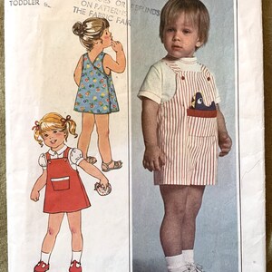 Pode incluir: Padrão de costura Simplicity número 8047 para uma criança de tamanho 1/2. O padrão inclui duas roupas: um vestido de macacão listrado vermelho e branco com uma blusa branca e um short de macacão listrado vermelho e branco com uma camiseta branca. O padrão também inclui uma peça de padrão para um brinquedo de pelúcia.
