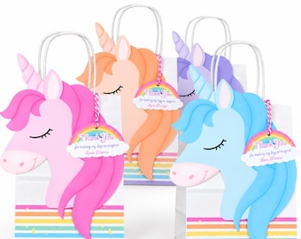May include: Three white paper gift bags featuring pink, peach, and blue unicorn cutouts with closed eyes and horns. Each bag has a rainbow-striped base and a rainbow-shaped tag that reads Thank You for making my day so magical Love, Marina.