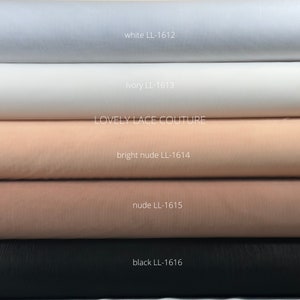 May include: Five rolls of tulle fabric in different colors: white, ivory, bright nude, nude, and black. Each roll has a label with the color name and a code, for example, "white LL-1612". The label "LOVELY LACE COUTURE" is visible on the third roll.