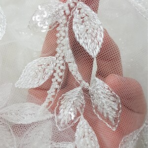 May include: White tulle fabric with delicate white beaded leaf embroidery.