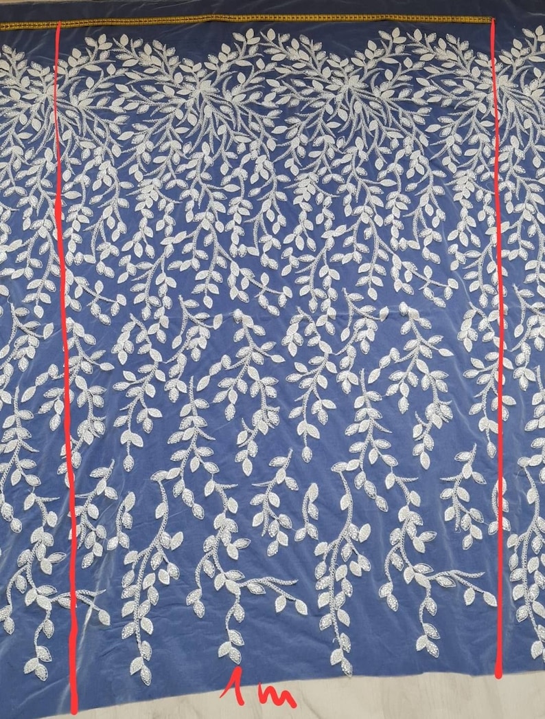 May include: White embroidered lace fabric with a delicate leaf pattern on a blue background. The fabric is 1 meter wide.