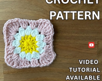 May include: A square crochet pattern with a daisy design. The center is yellow, surrounded by white petals, and framed by a pink border. The text "CROCHET PATTERN" is at the top, with "VIDEO TUTORIAL AVAILABLE" below.