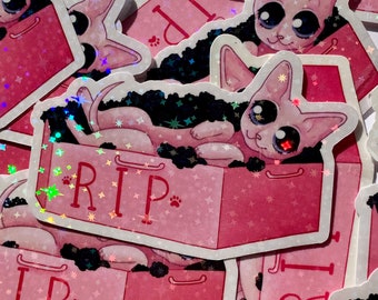 Puede incluir: Un conjunto de pegatinas holográficas rosas y negras con un gato de dibujos animados en un ataúd con el texto "RIP".
