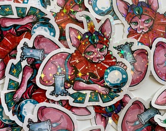 May include: A selection of stickers depicting a pink Sphynx cat in a fortune teller's attire. The cat is adorned in red and gold clothing, a jeweled headpiece, and holds a crystal ball. Tarot cards and a candle are also visible.