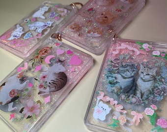 Peut inclure: Quatre porte-clés en plastique transparent avec des paillettes roses et différents motifs sur le thème des chats. Un porte-clés représente un chat rose et blanc avec un cœur rose, un autre représente deux chats tabby gris avec des fleurs, et les deux derniers représentent des chats roses et blancs avec des cœurs roses.