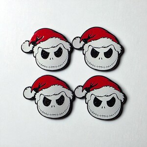 Pu&ograve; includere: Quattro spille smaltate identiche raffiguranti il volto rotondo, bianco e scheletrico di un personaggio con grandi occhi scuri e scintillanti e una bocca cucita, ognuna con un cappello da Babbo Natale rosso vivo con bordo bianco.