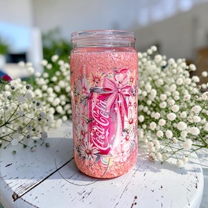 May include: A white ceramic mug with a black handle and the text "But First, Coffee" in a bold, black font. The mug is set against a plain white background.