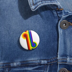 May include: A white button with a rainbow-colored design. The design features a series of curved lines in red, orange, yellow, green, blue, indigo, and violet.