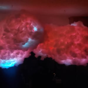 May include: Two large, fluffy white clouds with built-in LED lights. The cloud on the left is illuminated with blue light, while the cloud on the right is illuminated with red light.