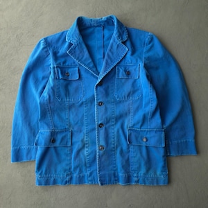 May include: A bright blue jacket featuring a collared neckline, long sleeves, and a button-down front closure. The garment includes two chest pockets and two lower pockets, each secured with a single dark button, matching the front buttons.
