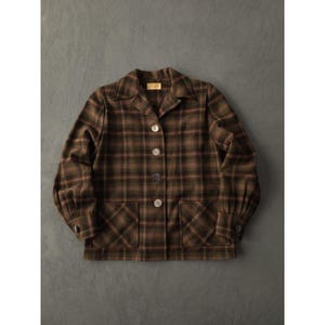 May include: A brown plaid jacket with a collared neckline, button-up front, and two front pockets. The jacket features a classic plaid pattern in shades of brown, green, and red. The sleeves have buttoned cuffs. The jacket is made of a soft, woven fabric.