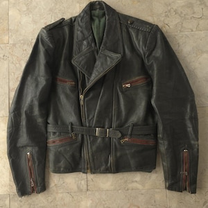 Puede incluir: Una chaqueta de cuero gris oscuro con cuello con solapas, cinturón en la cintura y bolsillos con cremallera. La chaqueta tiene detalles en rojo en los bolsillos y cremalleras. La chaqueta es de estilo clásico.