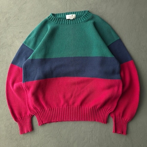 Peut inclure: Un pull à manches longues et col rond présentant des bandes horizontales color-block en bleu sarcelle, bleu marine et magenta. Le vêtement possède un col, des poignets et un ourlet en tricot côtelé, avec une petite étiquette blanche.