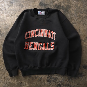 Op de afbeelding: Een zwart sweatshirt met lange mouwen en een ronde hals, voorzien van de tekst CINCINNATI BENGALS in oranje blokletters met witte omlijning op de borst. Het kledingstuk heeft een Russell Athletic label bij de hals en geribbelde boorden.