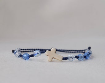 May include: A blue string bracelet with blue and clear glass beads and a white cross charm.