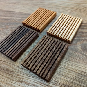 May include: Four wooden soap dishes in different shades of brown. The dishes have a grooved design to help drain water.