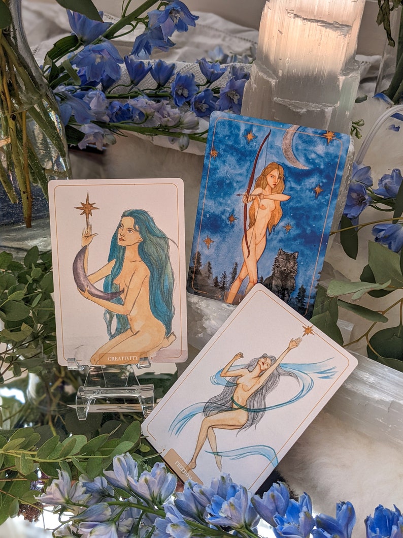 Puede incluir: Tres cartas de tarot con ilustraciones de mujeres e im&aacute;genes celestiales. Las cartas se titulan "Creatividad", "Libertad" y "La Luna".