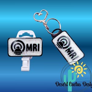 May include: Two MRI-themed accessories: a badge holder and a keychain. Both feature a white background with glitter, the MRI symbol, and the letters "MRI" in black. The keychain has a heart-shaped clasp.