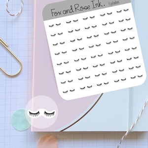 May include: A sheet of white sticker paper with black eyelashes printed on it. The sheet is labeled "Fox and Roe Ink. Eyelashes".