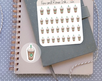 Peut inclure: Une feuille d'autocollants représentant 36 tasses de café illustrées de couleur marron avec de la crème fouettée et un cœur sur le dessus. Les autocollants sont disposés en grille. La feuille est blanche avec le texte "Fox and Roe Ink." et "FRAPPE" en noir. Il y a un seul autocollant représentant une tasse de café sur un fond transparent.