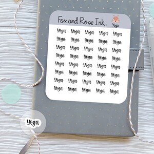 May include: A sheet of stickers with the words "Fox and Rose Ink." and "Yoga" printed on it. The stickers are white with black text and feature the word "Yoga" repeated 25 times.