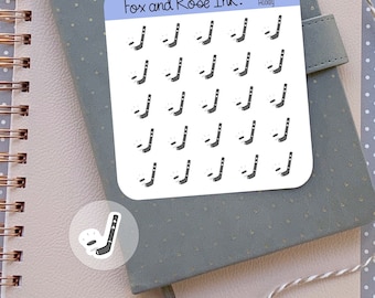 May include: A sheet of stickers featuring 25 hockey stick and puck illustrations. The stickers are white with black outlines and are arranged in a grid pattern. The text "Fox and Roe Ink." and "Hockey" are printed at the top of the sheet.