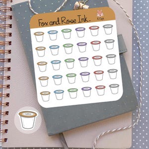 May include: A sheet of stickers featuring K-Cups in various colors, including brown, blue, green, purple, and red. The stickers are arranged in rows and columns. The text "Fox and Rose Ink." and "K-Cups" are visible. A single coffee K-Cup sticker is also shown.