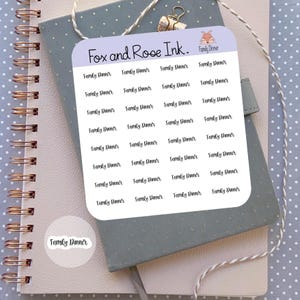 May include: A sticker sheet with the text "Family Dinner" repeated multiple times. The sheet is light purple and has rounded corners. The words "Fox and Rose Ink" are at the top. The stickers are on a notebook.