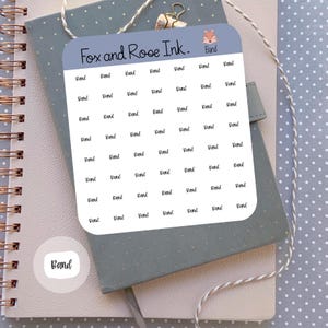 May include: A sheet of white stickers with the text "Band" repeated multiple times in a grid pattern. The stickers are on a grey background with a small fox illustration in the top right corner. The text "Fox and Rose Ink." is printed at the top of the sheet.