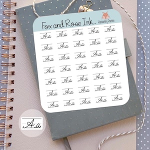 May include: A square sticker sheet with rounded corners featuring the text Fox and Rose Ink. Handwriting Practice at the top. The sheet contains multiple rows of the cursive letters Aa on lined paper guides. A single separate Aa sticker is included.