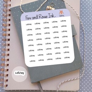 May include: A sticker sheet with the text "Gathering" repeated multiple times, along with a smaller sticker with the same word. The sheet is labeled "Fox and Rose Ink." with a fox illustration. The stickers are on a notebook.