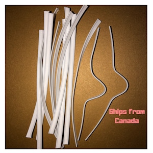May include: A selection of white, flexible nose wires for face masks, displayed on a gold-toned surface. The wires are thin and flat, with a slight curve. Some are straight, while others are bent into a curved shape. The text "Ships from Canada" is visible.