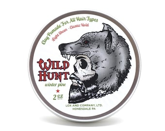 May include: A round metal tin of "Wild Hunt" clay pomade for all hair types. The label features a wolf head over a skull with a beard. The pomade is winter pine scented and contains 2 oz.