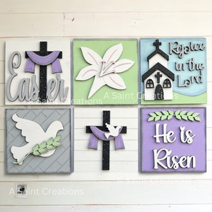 May include: Six wooden signs with Easter themes. The signs feature a cross with a purple scarf, a white lily, a church, a dove with an olive branch, a cross with a dove and a purple scarf, and a purple sign with the text "He is Risen".