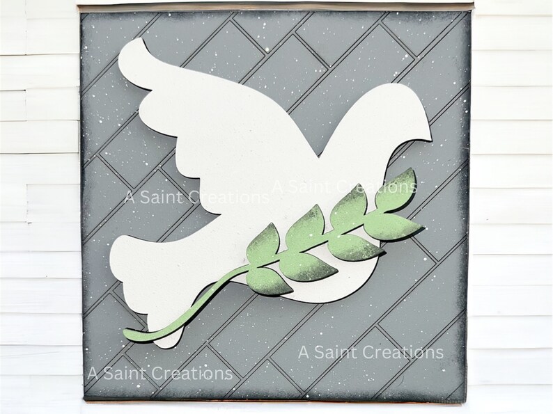 May include: A white wooden dove with an olive branch in its beak, on a gray background with a diamond pattern. The dove is a symbol of peace.
