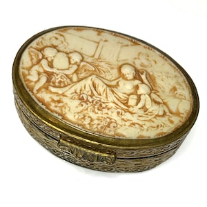 Oval Carved Bone Pill Box with etched brass case. Cherubs / Angels carved in bone.