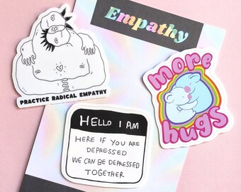 May include: Three stickers with a rainbow, black and white, and pink and blue color scheme. The stickers feature the text "Empathy", "Practice Radical Empathy", "More Hugs", and "Hello I Am Here If You Are Depressed We Can Be Depressed Together".
