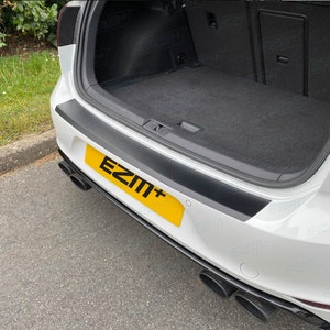 Puede incluir: Un coche blanco con un protector de parachoques negro. El protector de parachoques tiene un borde negro y una placa de matrícula negra con el texto "EZM+" en letras blancas.