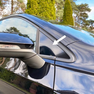 May include: A black car with black window trim. The window trim is visible in the top right corner of the image.