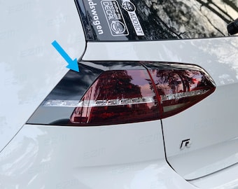 May include: A white car with a black rear taillight and a "dadswagen" sticker on the back window. The taillight has a black trim around it and a red lens with a white LED strip.
